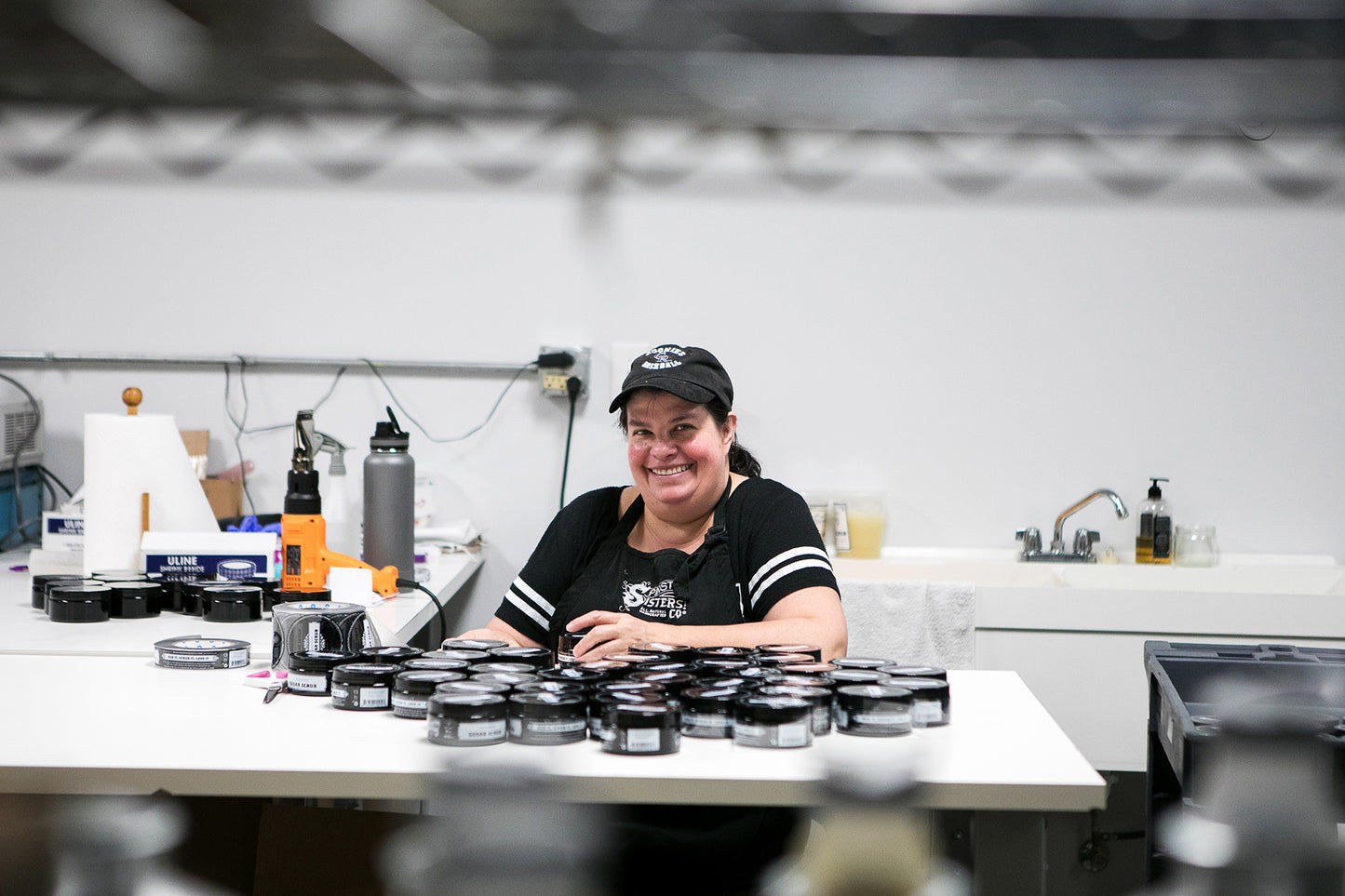 Woman smiling at a work space surround by assorted products