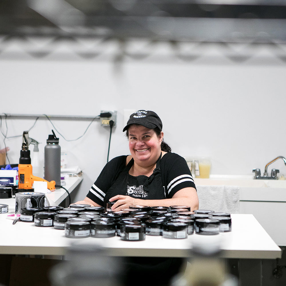 Woman smiling at a work space surround by assorted products